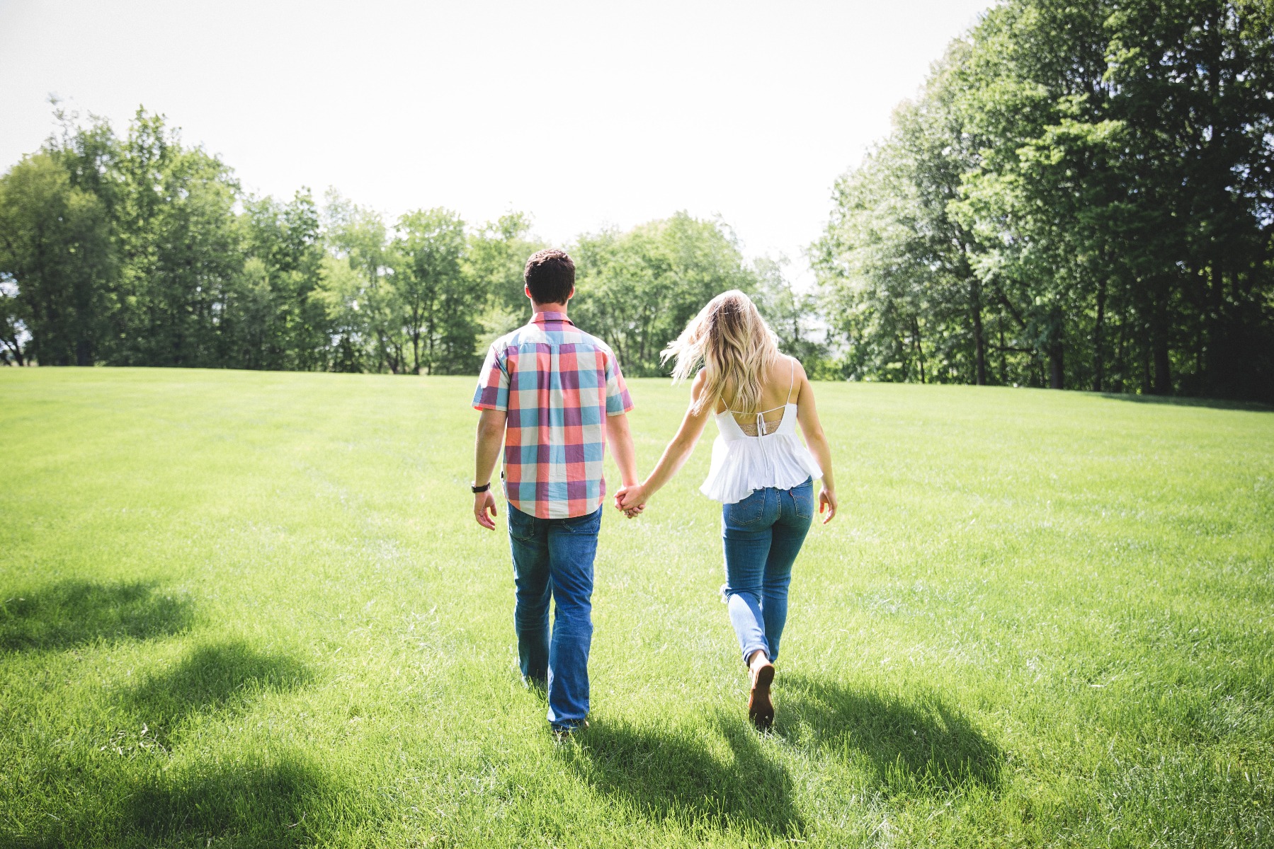 Man and woman standing side-by-side holding hands.