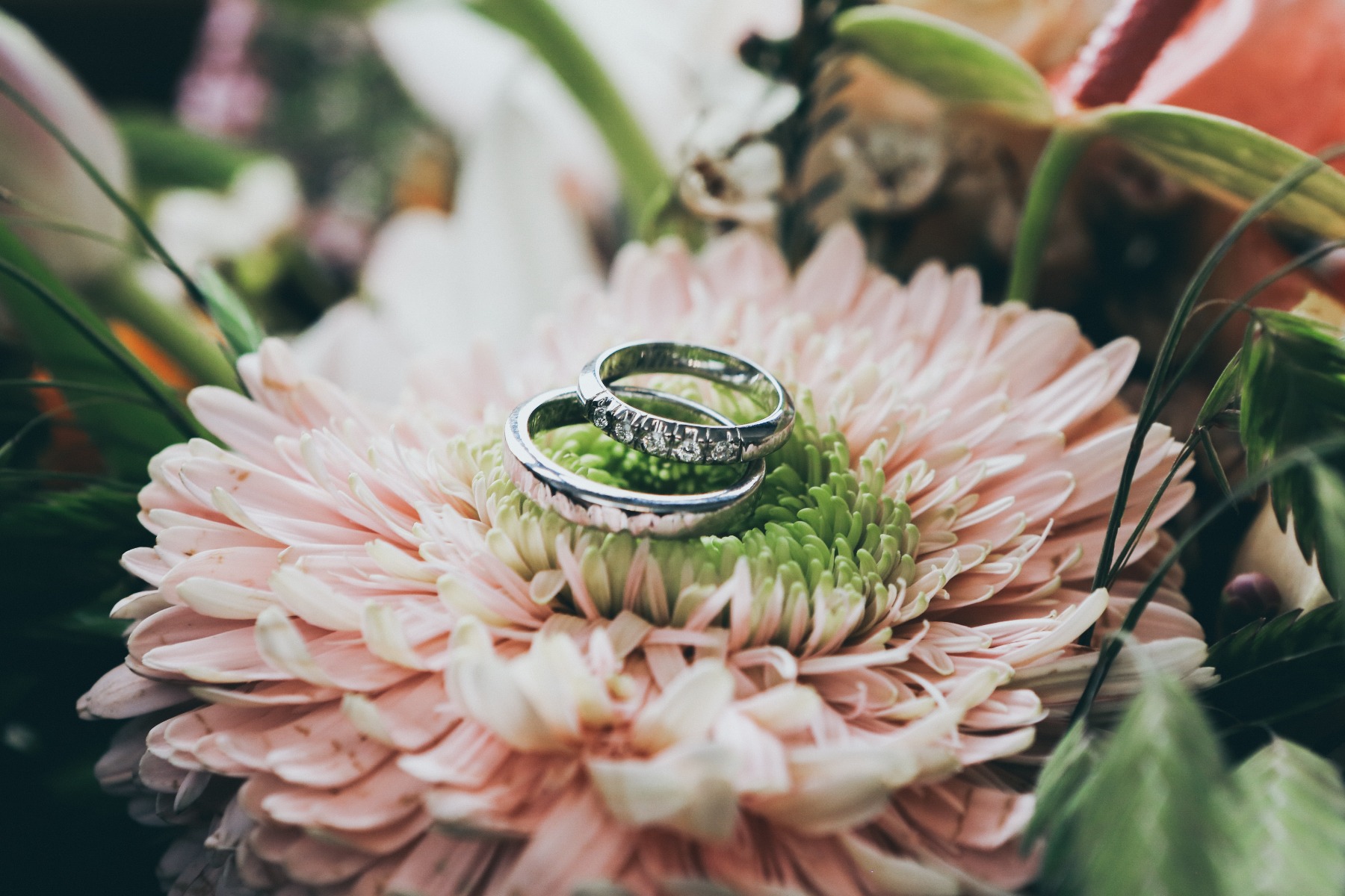 Man holding an engagement ring and a bouquet of flowers. 