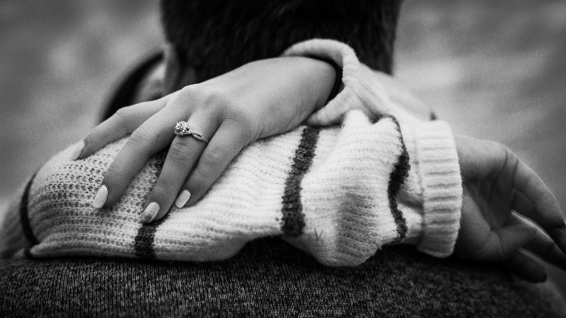 Black and white image of a woman showing off her engagement ring.