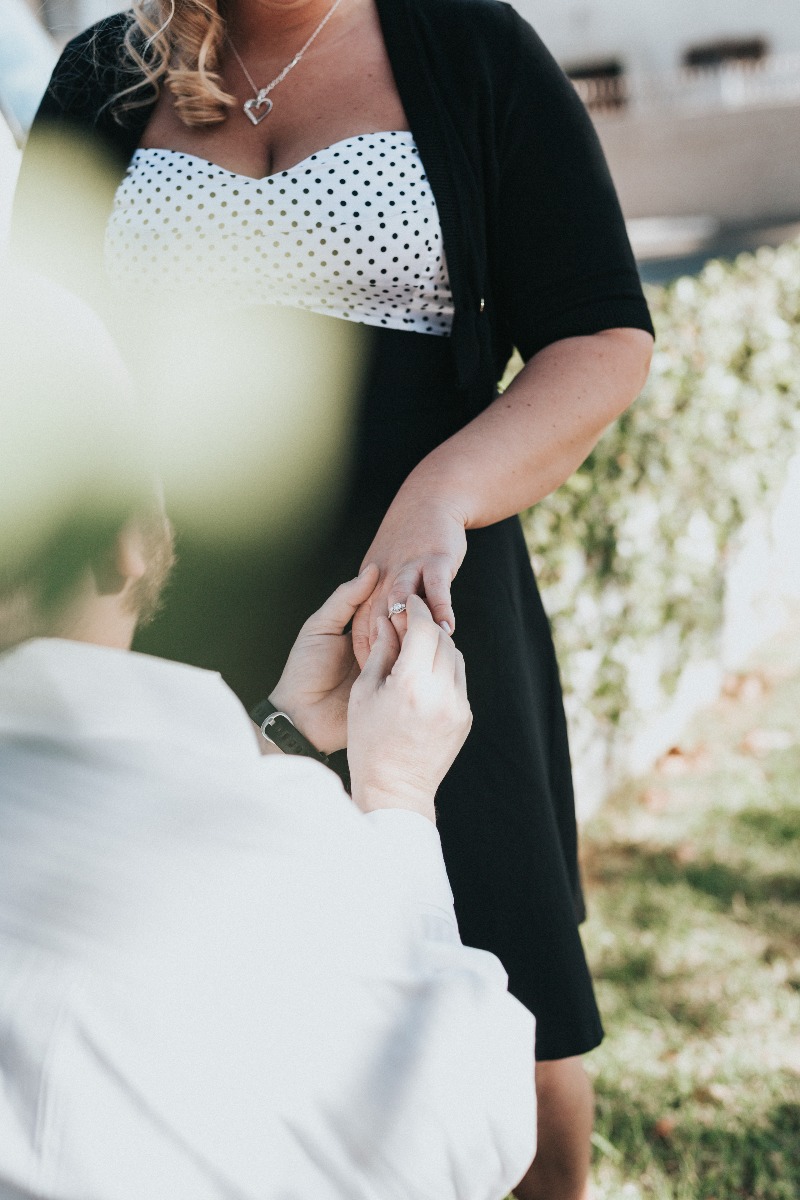 Man on one knee proposing to his girlfriend on the steps of their house. 